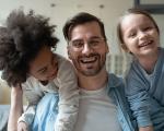 man smiling on a sofa with a happy child on either side of him