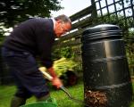 A photo of a man shovelling compost from the bottom of a compost bin