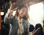 smiling lady on a bus holding onto an overhead handle