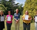 Four people holding certificates with a member of council staff