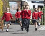 children in red sweatshirts running in a playground