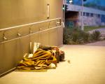 person sleeping rough under a blanket in a lit underpass