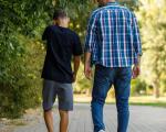 A photo of an adult man with boy walking in a park