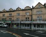 A row of shops with scaffolding outside the front of the buildings.