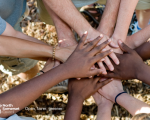 Close up of peoples hands on top of each others in a circle, with the council logo and 'open., fairer, greener.'