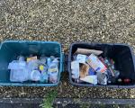 Two full recycling boxes on top of gravel. The right-hand box contains mixed paper and cardboard