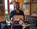 Gagandeep holding a Breastfeeding Welcome sign and smiling at the camera