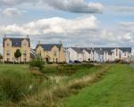 A row of houses, with a pond and green space in front of them