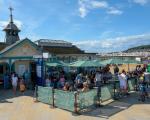 The Victorian cafe on a sunny day. People sit outside the building under umbrellas, and the beach is visible in the background