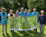 A group of volunteers stand in a park holding up their Green Flag