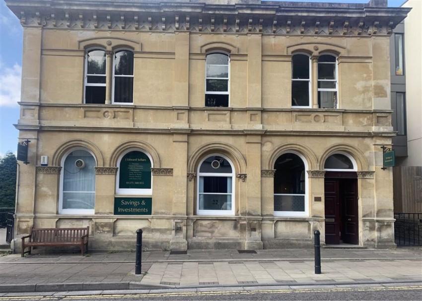 A front view of a vacant Victorian stone building with arched windows and front door. 