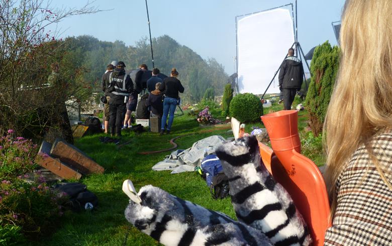 a camera crew sets up equipment in the graveyard of St Andrews church, while a blonde woman stands in the foreground