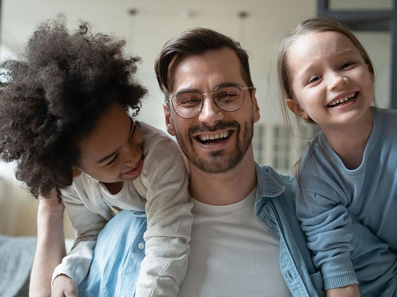 man smiling on a sofa with a happy child on either side of him