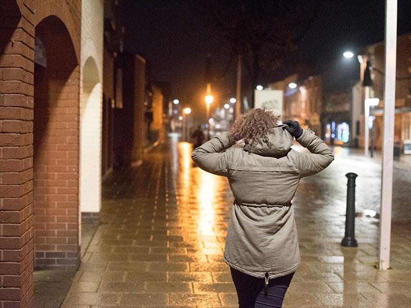 Woman walking down a street in the dark