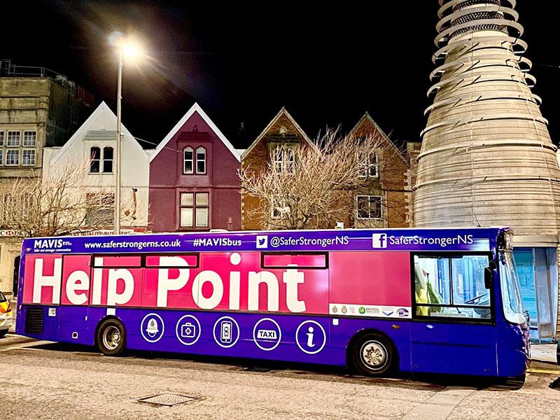 purple bus with 'help point' written on the windows against the night sky