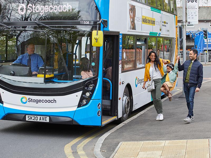 family boarding a bus - the parents are swinging their young child between them