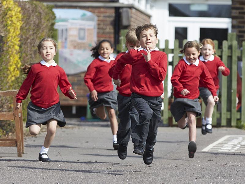 children in red sweatshirts running in a playground