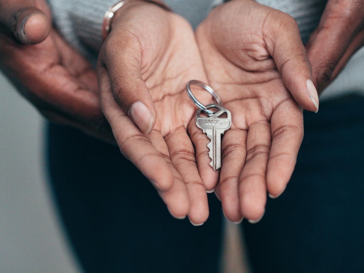 two people holding hands, showing their palms and holding a key