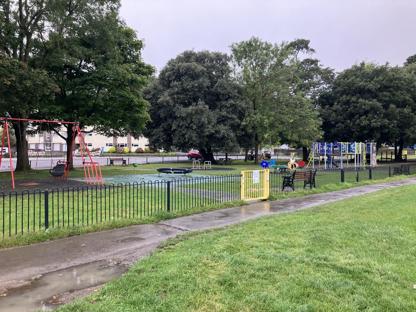 A photo of the children's play area at Salthouse Fields in Clevedon. The image shows a gated area with swings, a climbing frame and other play equipment.