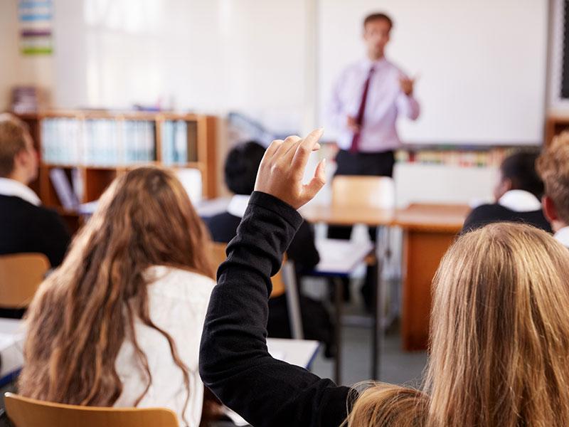 pupils putting hand up in a classroom