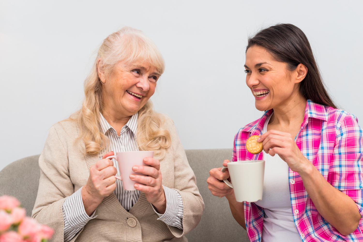 Two people having drinks together - one holding a biscuit