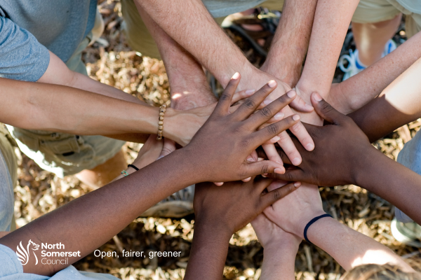 Close up of peoples hands on top of each others in a circle, with the council logo and 'open., fairer, greener.'