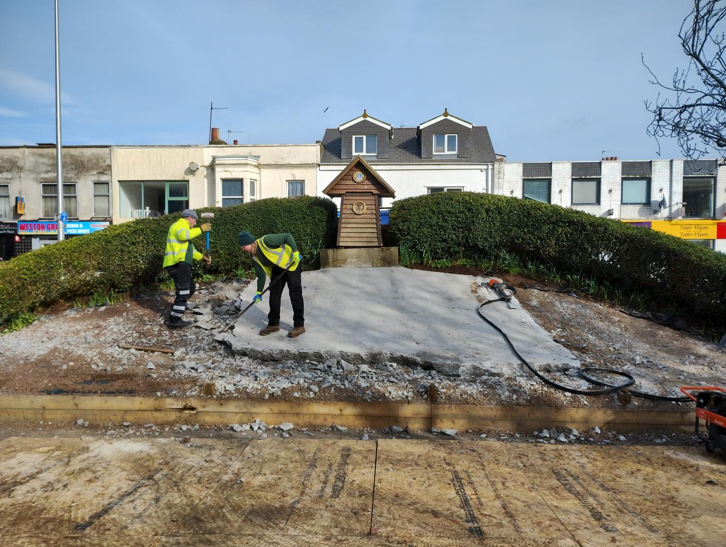 Two contractors swing hammers to remove the concrete covering on the floral clock at Weston-super-Mare