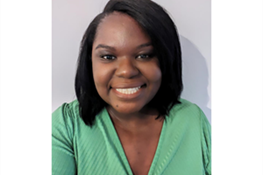 A headshot photograph of a dark skinned woman with shoulder length straight dark hair. She is wearing a green top and is friendly and smiling towards the camera.