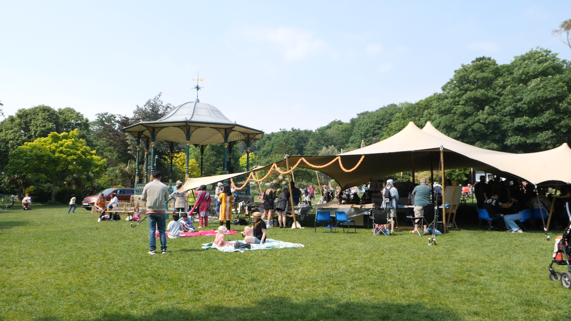 A photo of a stretch tent in Grove Park with people enjoying a summer event