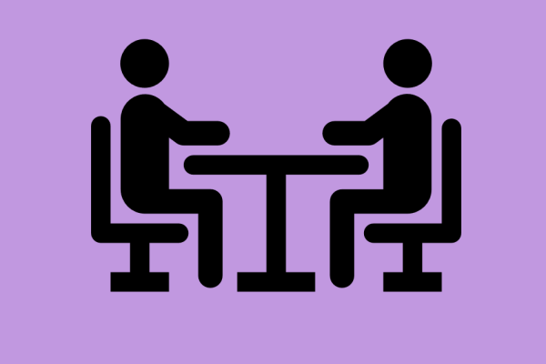 An icon showing two figures sitting at a desk talking to each other